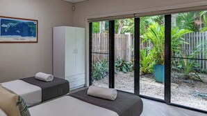 Ein Zimmer mit zwei Betten, einem großen Fenster und Blick auf einen Garten.
