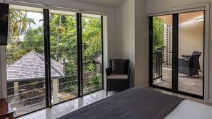 Ein Schlafzimmer mit einer großen Schiebeglastür, die auf einen Balkon mit einem Stuhl und einem Tisch führt.