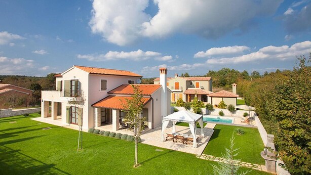 Una villa moderna con piscina, patio coperto e prato curato.
