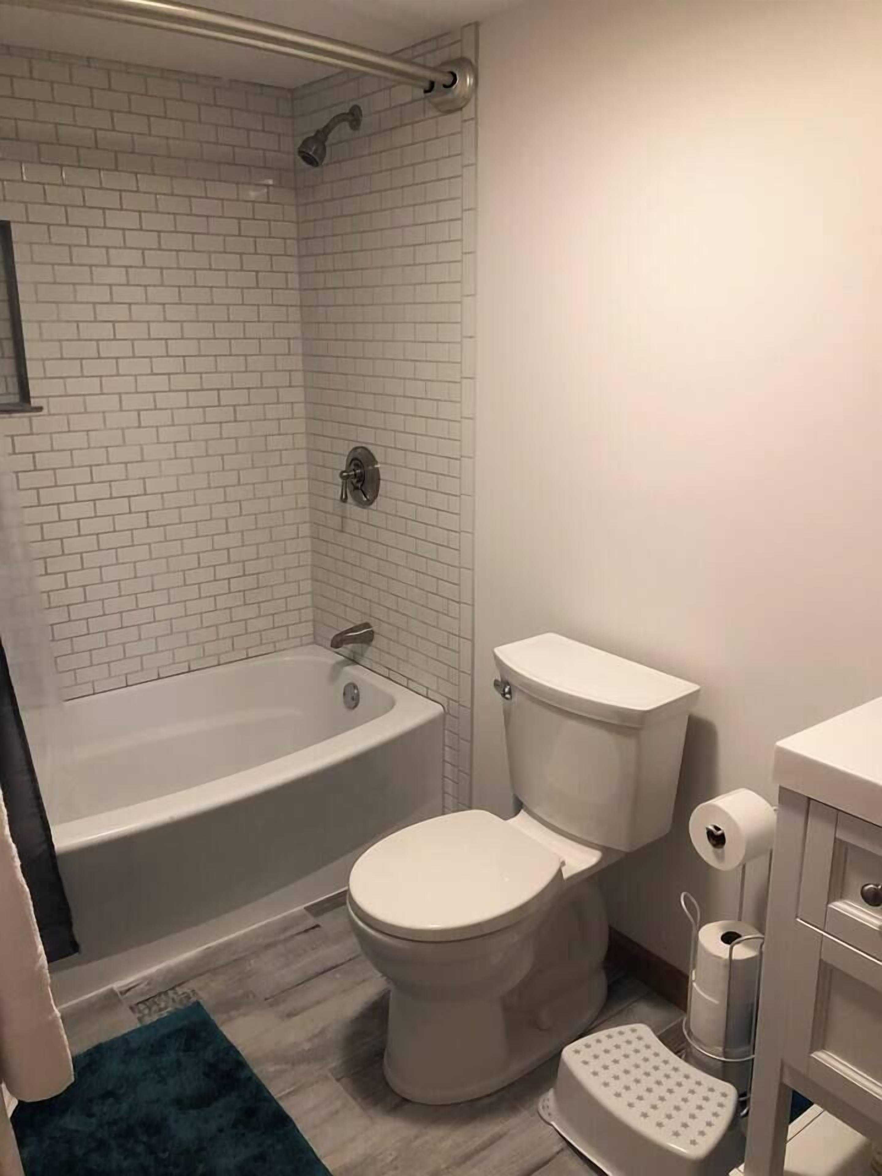 Un baño con una bañera blanca, inodoro y zona de ducha.