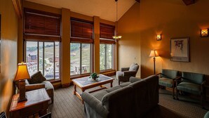 A cozy living room with large windows, a fireplace, and a view of the countryside.