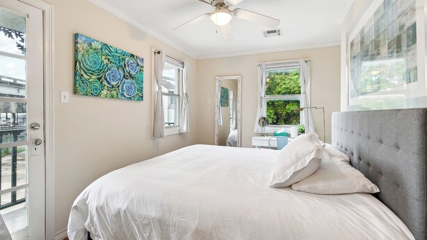 A bedroom with a large bed, a ceiling fan, and a window with curtains.