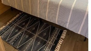A wooden cabin room with a bed, pillows, and a rug. - Between the Waters Rustic Retreat (Hilham)