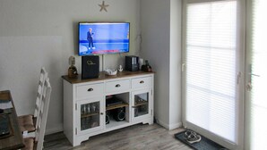 Una stanza con una TV su un mobile in legno, una decorazione a stella sul muro e una porta scorrevole in vetro.