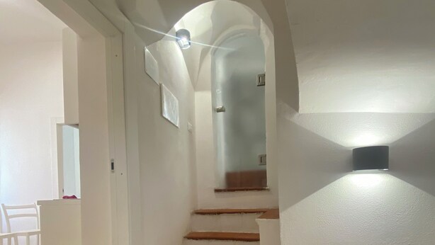 A staircase with white walls and brown steps leading to a second floor. - Delightful one-bedroom apartment in the heart of the historic Gaetano center. A stone's throw from the sea (Gaeta)