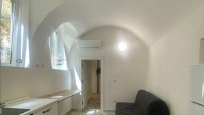 A compact kitchen with a built-in oven, a black sofa, and a window providing natural light. - Delightful one-bedroom apartment in the heart of the historic Gaetano center. A stone's throw from the sea (Gaeta)