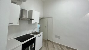 A small, modern kitchen with white cabinets, a black countertop, and a built-in oven. - Delightful one-bedroom apartment in the heart of the historic Gaetano center. A stone's throw from the sea (Gaeta)