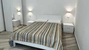 A modern bedroom with a bed, bedside tables, and a wardrobe. - Delightful one-bedroom apartment in the heart of the historic Gaetano center. A stone's throw from the sea (Gaeta)