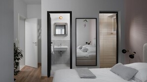A modern bedroom with a bed, a bedside lamp, a mirror, and a window with blinds. - Gorgeous home in Zadar (Zadar)