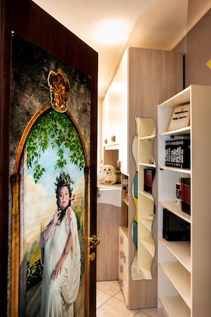Una stanza con una porta in legno, una libreria e un quadro.