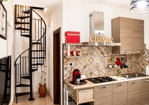 Una cocina con estufa, cafetera y un armario con la etiqueta 'Cuisine'.