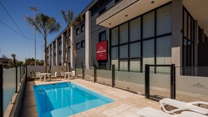 A hotel with a swimming pool, outdoor seating, and a red sign indicating it is a hotel. - Fuente Mayor Hotel Terminal (Mendoza)