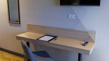 Una habitación moderna con escritorio, silla y televisor montado.