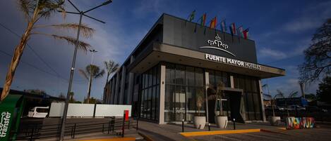 Un edificio moderno de hotel con un letrero destacado que dice "FUENTE MAYOR HOTELES".