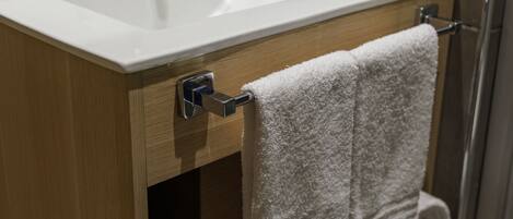 A bathroom with a white sink, wooden cabinet, and two towels hanging on a rack.