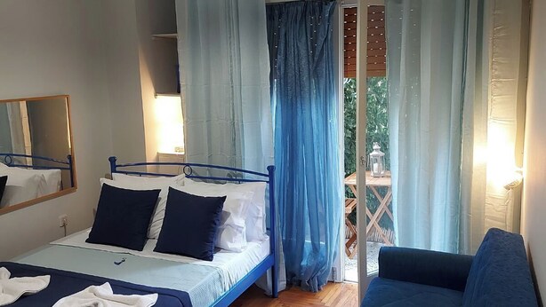 A bedroom with a bed, a sofa, a hanging light fixture, and a window with curtains. - Comfortable, friendly, fully equipped apartment (Athina)