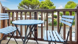 Une terrasse en bois avec une table ronde et deux chaises.