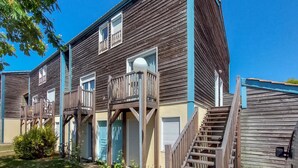 Un bâtiment en bois à deux étages, doté de balcons, d’un escalier et d’un petit jardin.