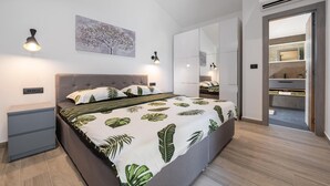 A modern bedroom with a bed, bedside tables, a nightstand, a large mirror, and a wardrobe. - Luxurious home in Labin with private swimming pool, can be inside or outside (Labin)