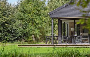 A modern house with a covered patio area, a dining table, and chairs. - Nice home in Grenaa with WiFi (Grenaa)