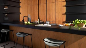 Una cocina moderna con armarios de madera, encimera negra y dos taburetes de bar.