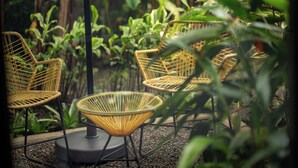 Wicker chairs and a table set outdoors with a gravel ground, surrounded by greenery. - Suwa Villa Arenal | Amazing Location in La Fortuna (la fortuna, calle 468, avenida 335)