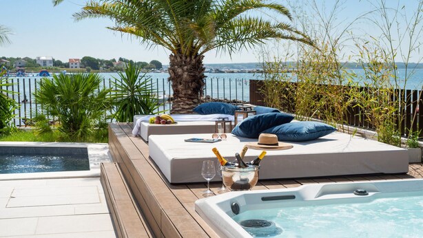 A poolside area with a hot tub, lounge seating, and a view of the sea. - Beach front home in Privlaka (Privlaka)
