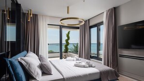 A modern bedroom with a bed, large windows, a view of the sea, and a TV. - Beach front home in Privlaka (Privlaka)