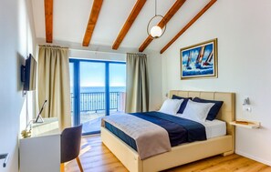 A bedroom with a bed, a desk, a chair, a painting, and a view of the sea. - 3 bedroom stunning home in Ivan Dolac (Ivan Dolac)