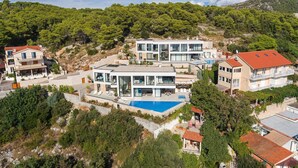 Una villa moderna con piscina, rodeada de exuberante vegetación y colinas.