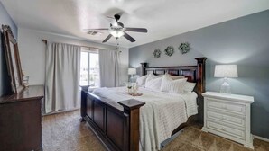 A bedroom with a bed, a nightstand, a ceiling fan, and a window with curtains. - Sandstone Bliss - 3 bed, 2.5 Bath Cozy Home! (Mesa)
