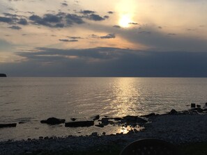 Un coucher de soleil sur une mer calme, avec une côte rocheuse.