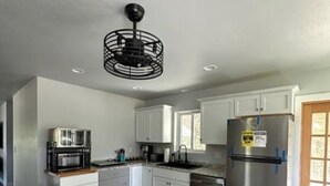 Una cucina moderna con mobili bianchi, elettrodomestici in acciaio inossidabile e pavimento in legno.
