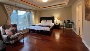 A hotel room with a bed, a chair, a desk, and a window with curtains.