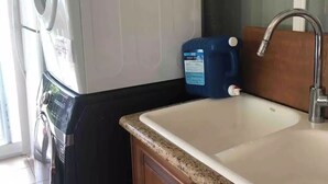 A compact kitchen with a washing machine, a sink, and a blue detergent bottle. - A comfortable two-bedroom with even a king size bed , close to YVR Richmond (Richmond)