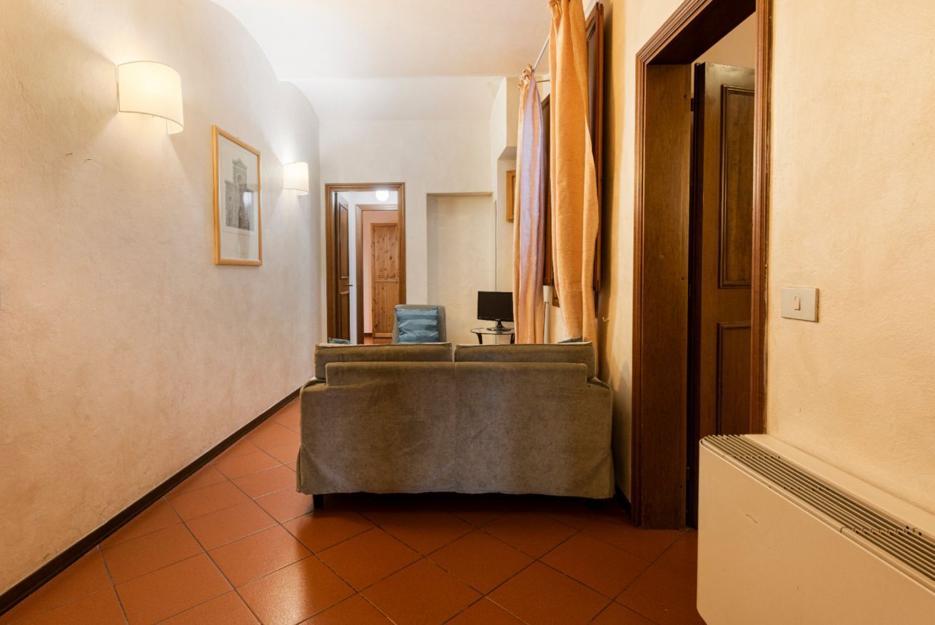 A hallway with a sofa, a framed picture, a lamp, and a door.