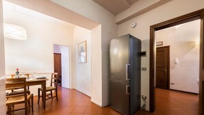 Une cuisine équipée d’un réfrigérateur, d’une table à manger avec des chaises et d’un luminaire.