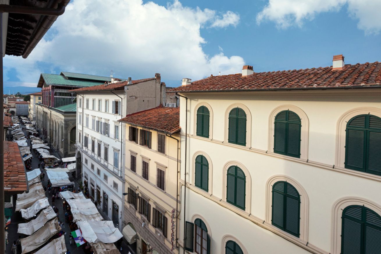 A street view with buildings, some with green shutters, and a clear sky.
