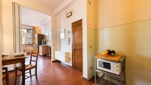Una cocina con una mesa de comedor, sillas, microondas y una puerta de madera.