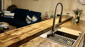 Una cocina moderna con encimera de madera, un lavamanos integrado y una lámpara colgante.
