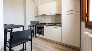 Une cuisine de taille réduite, avec des meubles blancs, une cuisinière et un four à micro-ondes.