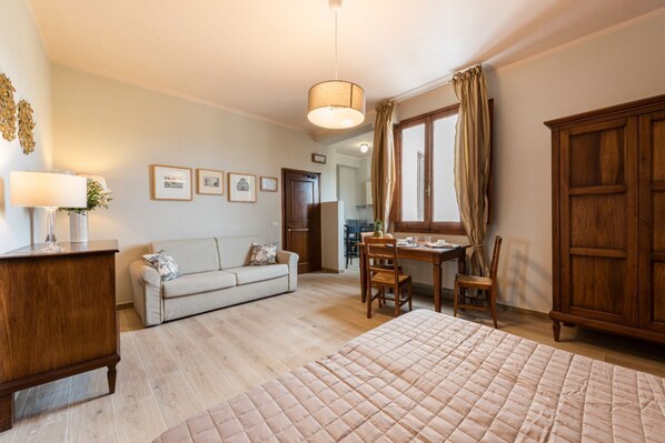 Une chambre à coucher comprenant un lit, un bureau, une chaise, un canapé, une armoire et une lampe.