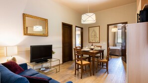 Ein Wohnzimmer mit Fernseher, Sofa und Essbereich mit Stühlen und Tisch.
