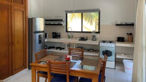 Une cuisine compacte avec un coin repas, comprenant un réfrigérateur, une cuisinière, un évier et un ventilateur de plafond.