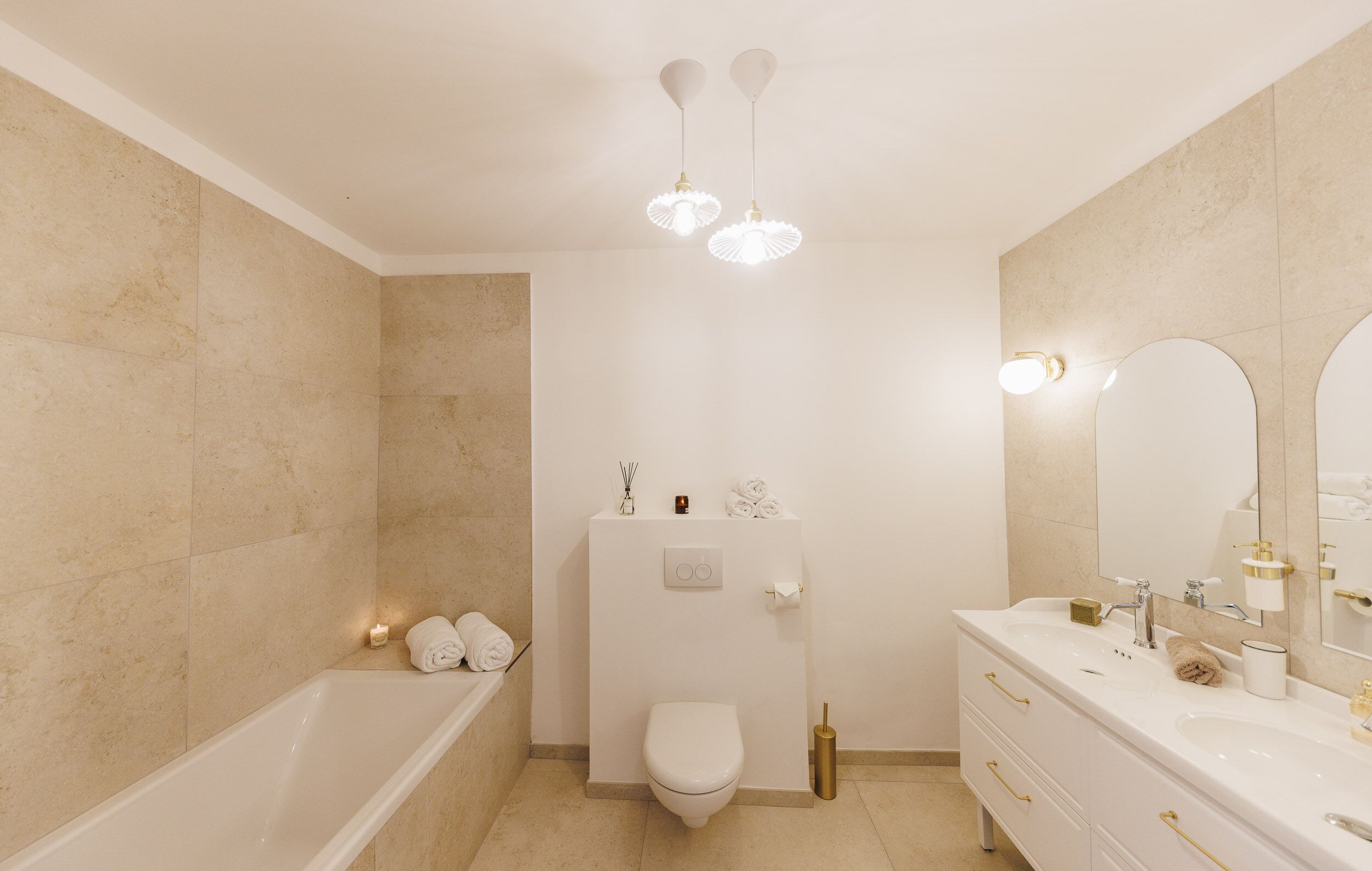 Une salle de bain moderne équipée d’une baignoire, de toilettes et d’un meuble-lavabo avec un grand miroir.