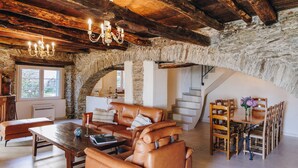 A rustic interior with a stone wall, leather furniture, and a staircase.