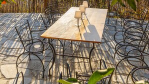 An outdoor dining area with a table and chairs, surrounded by a vineyard and a view of the hills.