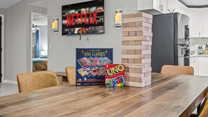 Un comedor con una mesa de madera, un juego de mesa y un televisor que muestra Netflix.