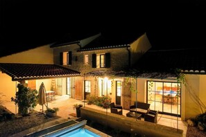 Ein zweistöckiges Haus mit Swimmingpool, Sitzbereich im Freien und einer Terrasse.