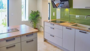 A modern kitchen with a wooden countertop, a built-in sink, and light-colored cabinets. - Awesome home in Violes (Violes)
